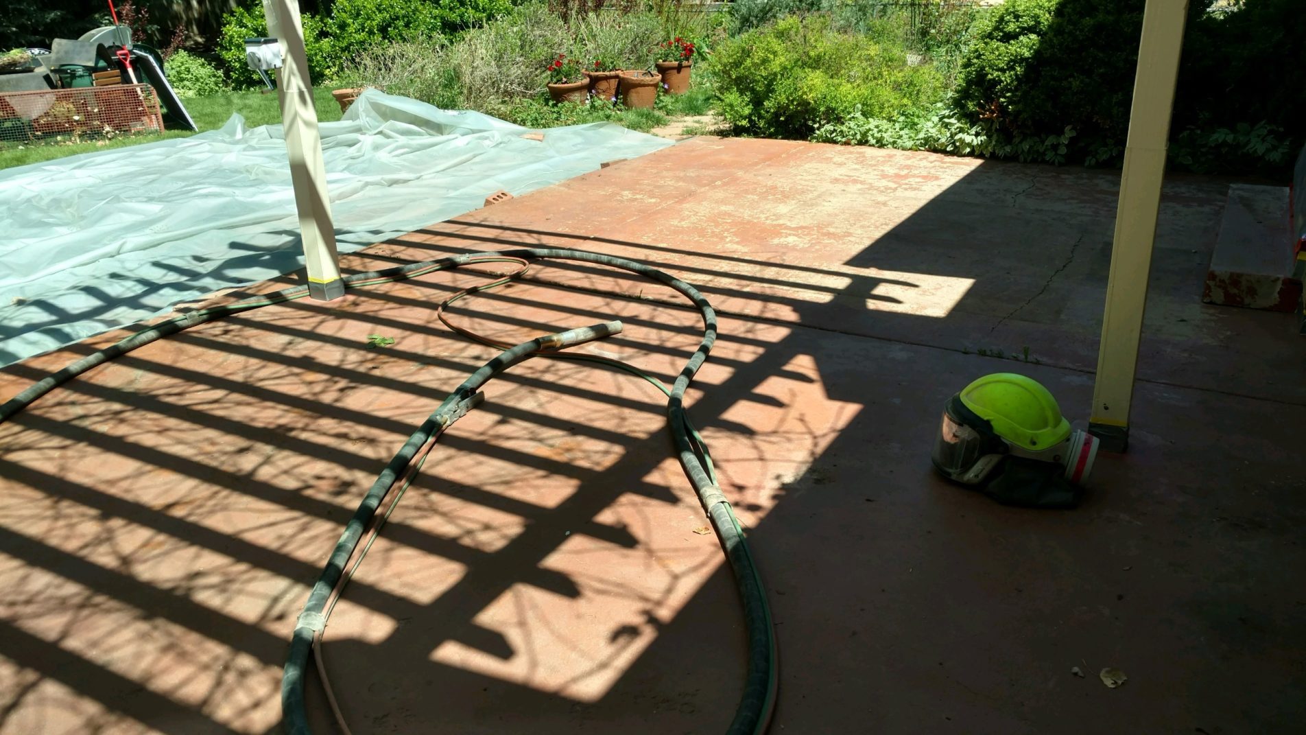 concrete back patio with tarp for restoration by blast from the past